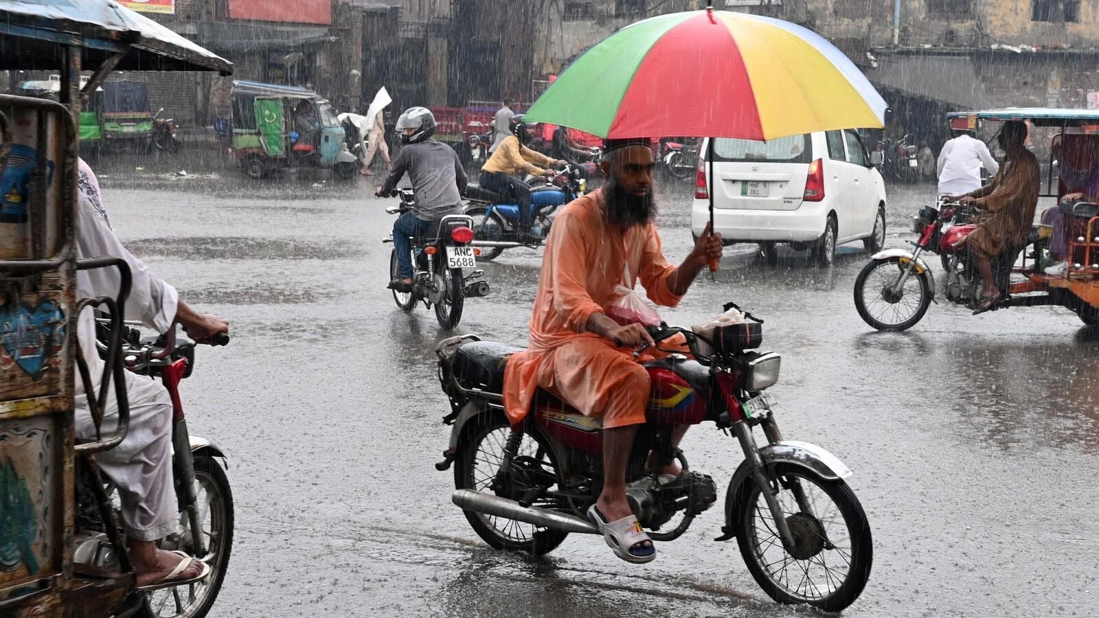 A commuter rides his motorcycle through a road amid heavy monsoon showers