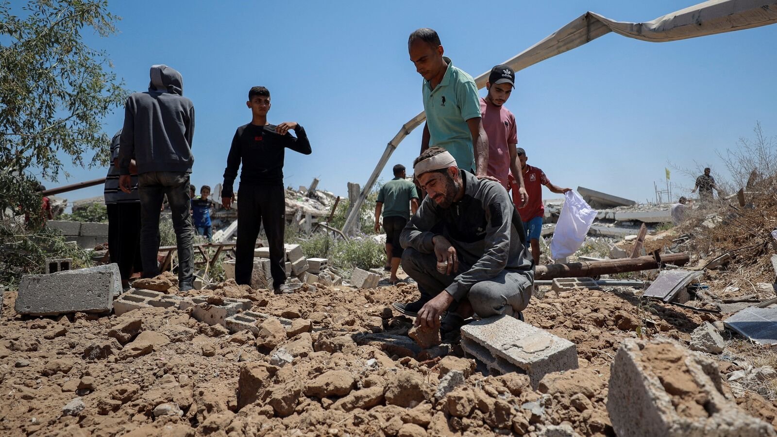Hossam Azzam reacts at the grave of his son Ameer and other relatives, killed in an overnight Israeli strike on their house, according to medics, after burying them in a plot of land due to the lack of space in Gaza's overcrowded cemeteries, in Gaza City