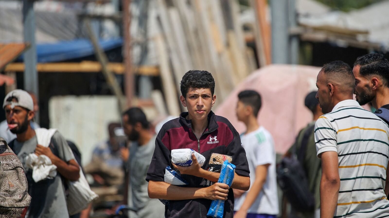 Displaced Palestinians at the Nuseirat refugee camp haul food parcels and other items they managed to get from a GHF aid distribution point in the central Gaza Strip on July 26, 2025.  (Photo by AFP)