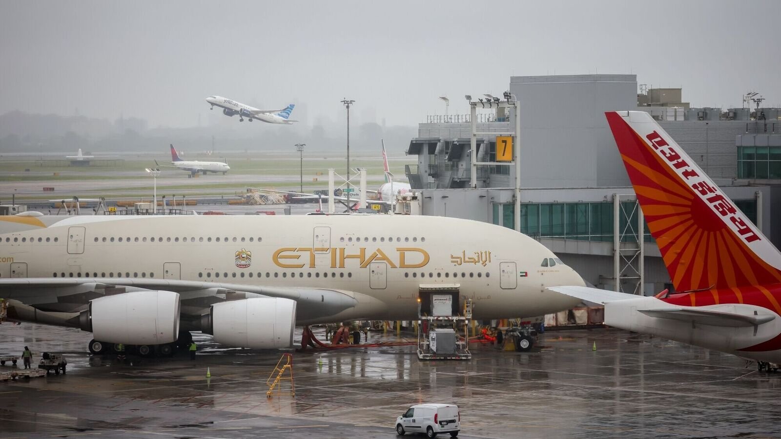 A JetBlue plane takes off behind an Etihad Airways and Air India plane at Terminal 4 of John F. Kennedy International Airport (JFK) in New York, US, on Monday, June 9, 2025.