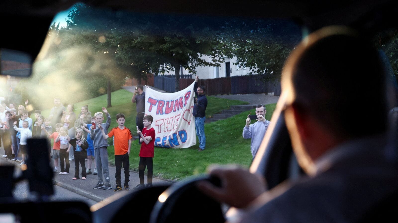 People wave as a motorcade carrying U.S. President Donald Trump drives to Turnberry, Scotland, Britain, July 25, 2025. REUTERS/Evelyn Hockstein
