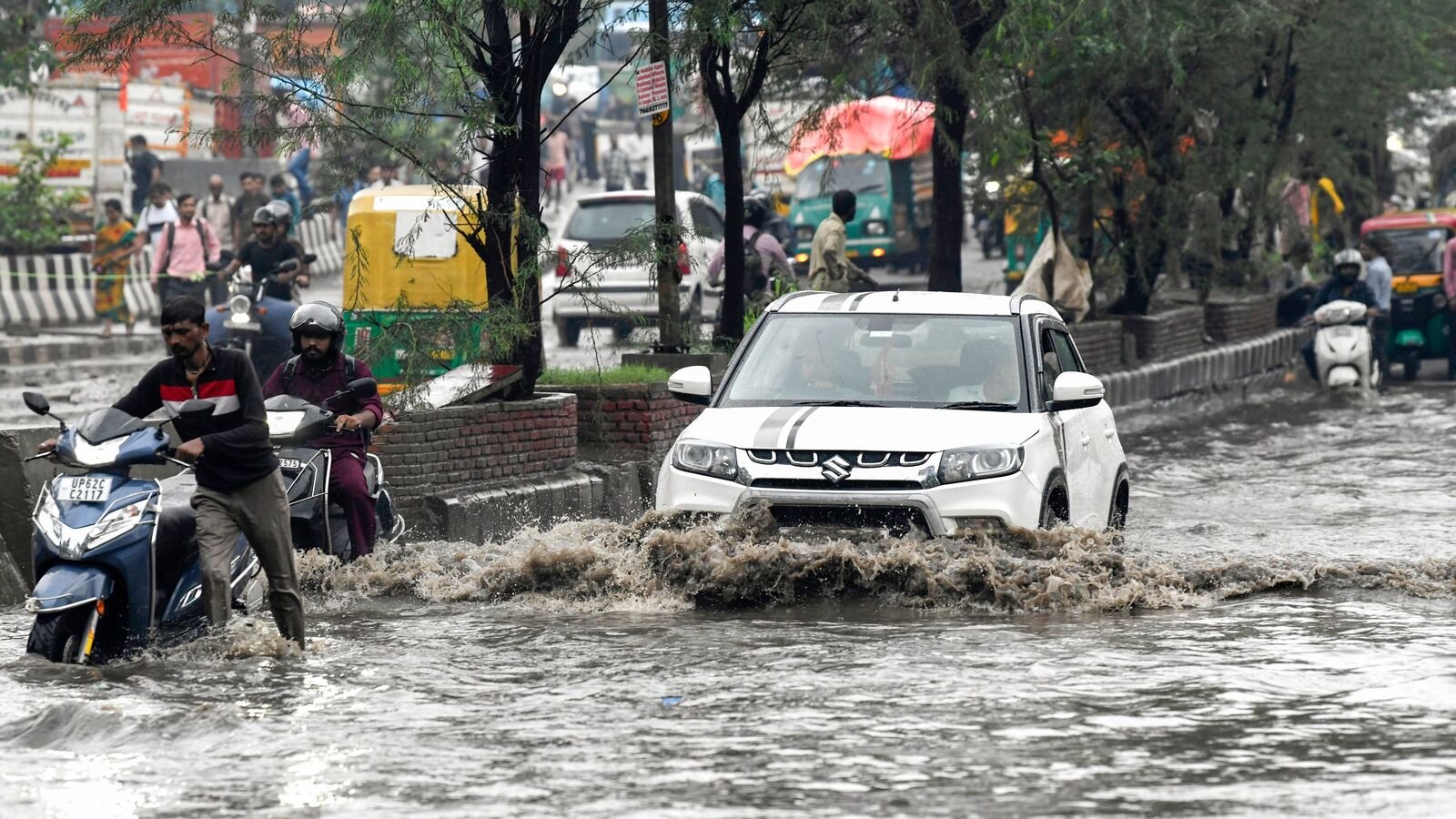 Commuters wade through a waterlogged road after heavy rainfall, in New Delhi on Wednesday.