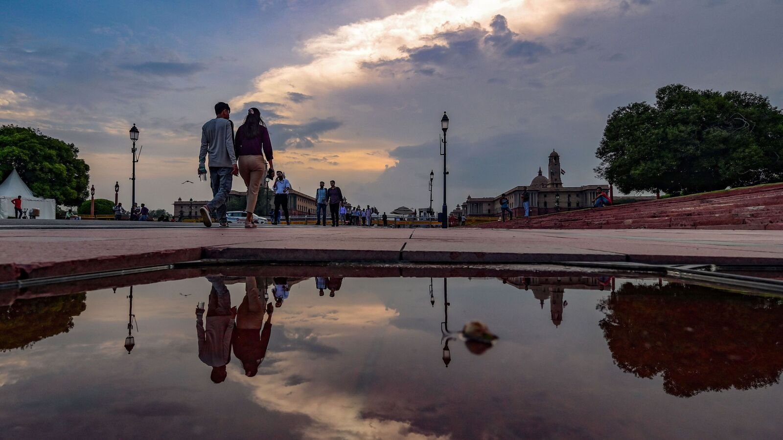 Office-goers walk under a clear blue sky after rain at the Vijay Chowk area in New Delhi. (Photo by Raj K Raj / Hindustan Times)