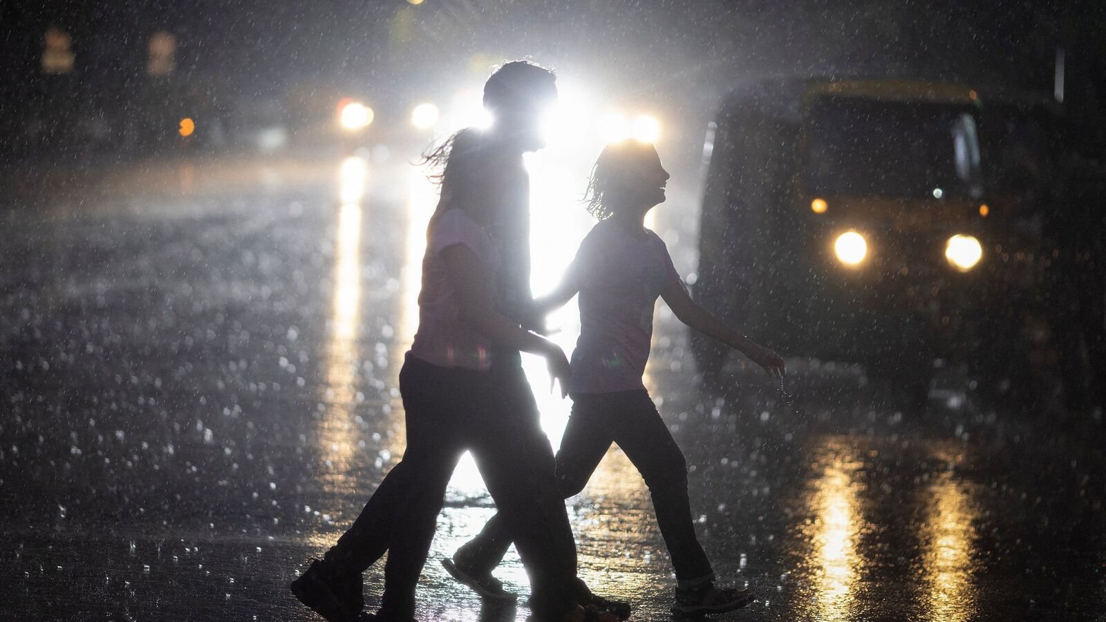 A family crosses a street during heavy rains in New Delhi on July 14, 2025.