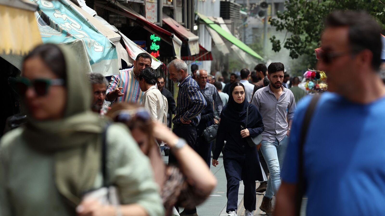 Iranian walk past shops on a sidewalk in the capital Tehran on July, 9, 2025. (Photo by AFP)