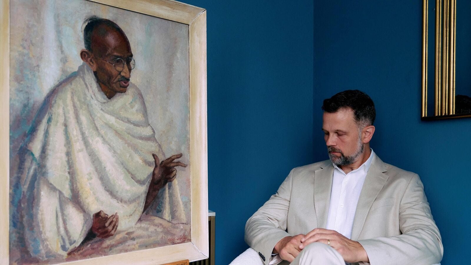 Caspar Leighton, great-nephew of British-American artist Clare Leighton, poses with a painting by his great-aunt of Indian independence leader Mahatma Gandhi at Bonhams auction house in London on June 9, 2025. Gandhi. (Photo by BENJAMIN CREMEL / AFP)