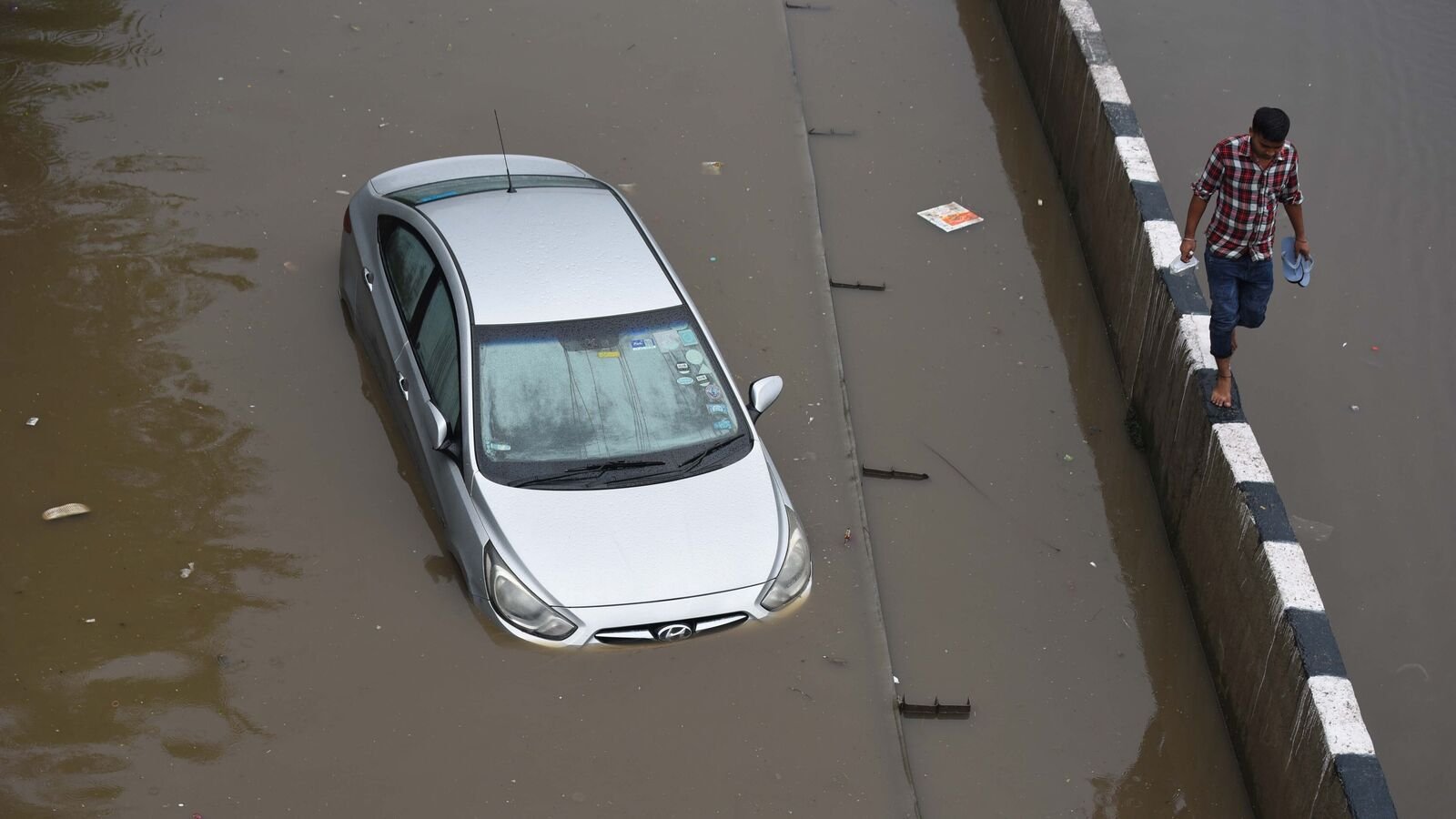 A car stuck on waterlogged stretch after the heavy rains National Highway-48 service road near Narsinghpur village, in Gurugram