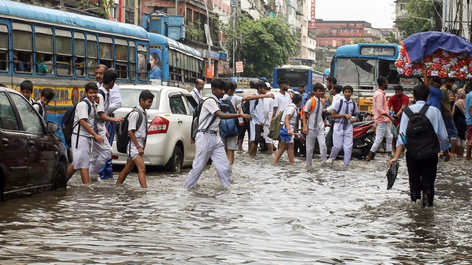 Kolkata rains: Traffic snarls in West Bengal's capital following heavy rainfall as school children wade through a severely waterlogged road on July 25.