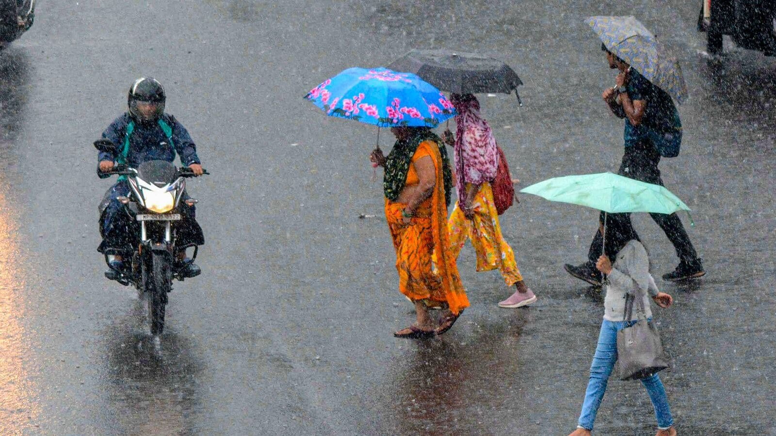 Pedestrians walk on Bhopal road amid heavy rainfall on Thursday, July 17.