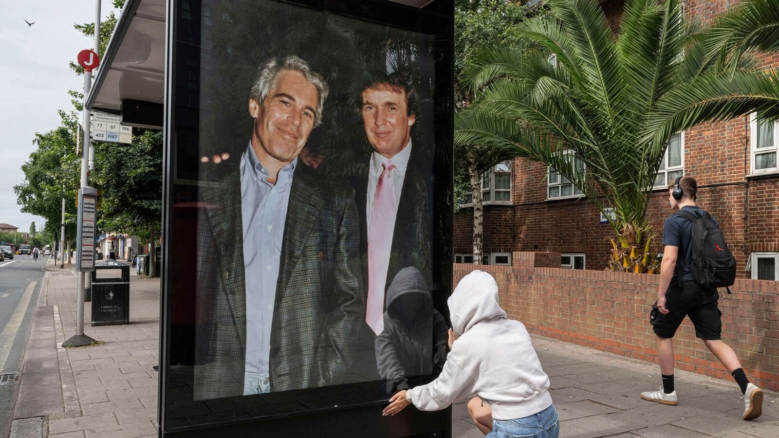 Activists put up a poster showing President Donald Trump and Jeffrey Epstein near the US Embassy