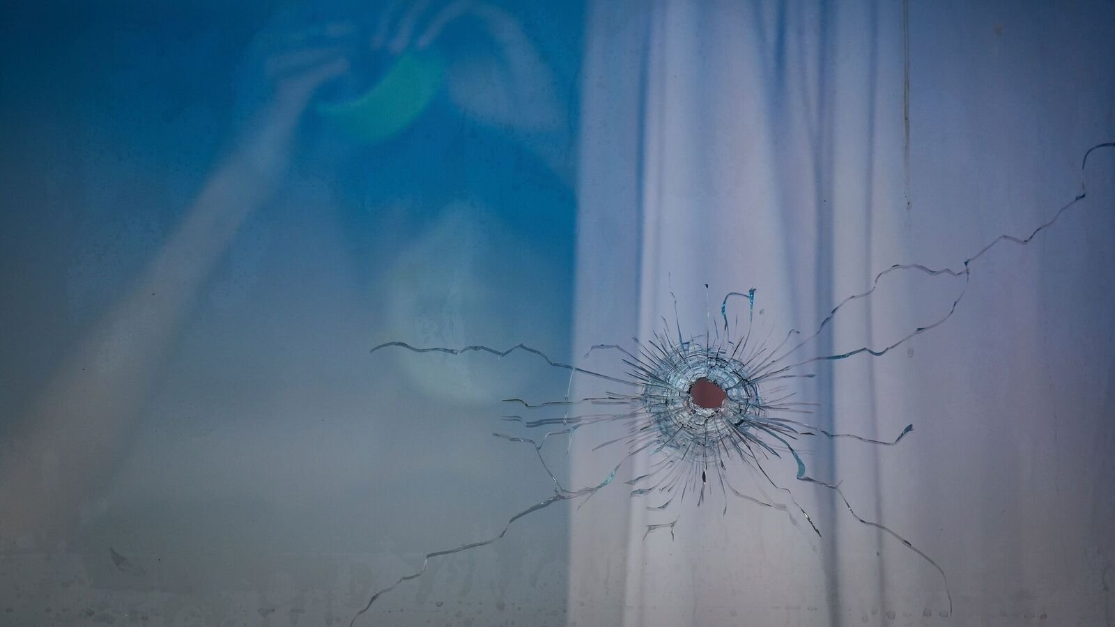A bullet hole is seen in the window of a cafe as a worker tapes plastic sheeting over the windows, in Surrey, British Columbia, Thursday, July 10, 2025, while Surrey Police investigate shots that were fired at Kap's Cafe, which is linked to comic and television host Kapil Sharma, who posted a video of the new establishment on Instagram this week. (Darryl Dyck/The Canadian Press via AP)
