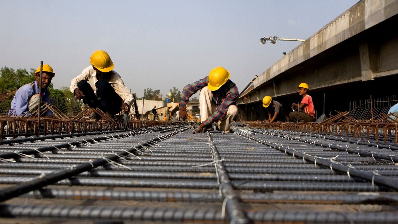 Construction workers prepare steel rebar rods for reinforcing concrete, on an overpass construction site on India's National Highway 8, in Gurgaon, India, on Tuesday, April 24, 2007. In the past six months, the government has cut import tax on wheat and excise duties on fuel and steel to beat down prices. Photographer: Sanjit Das/Bloomberg News