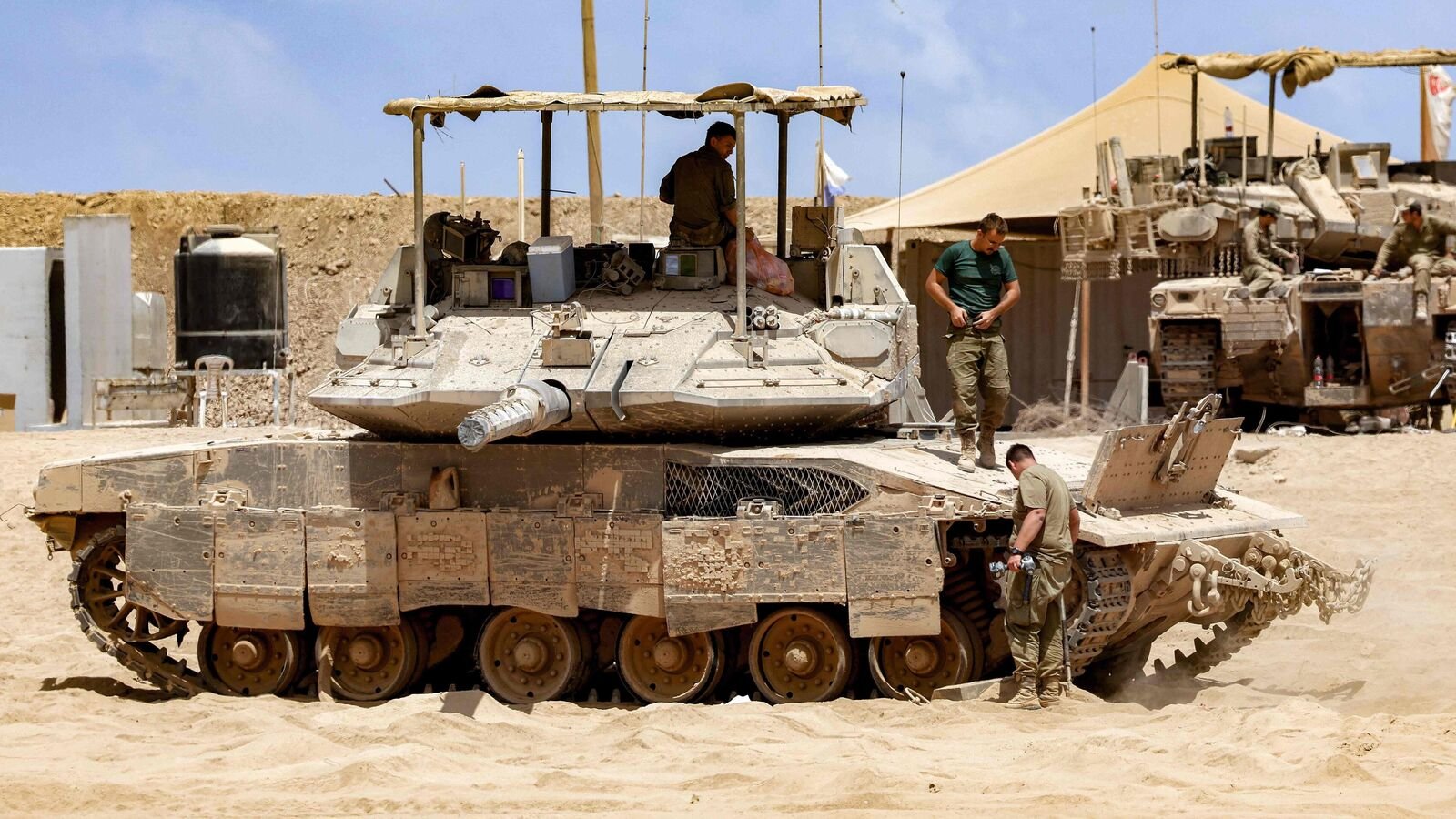 Israeli army soldiers inspect a main battle tank positioned near the border with the Gaza Strip