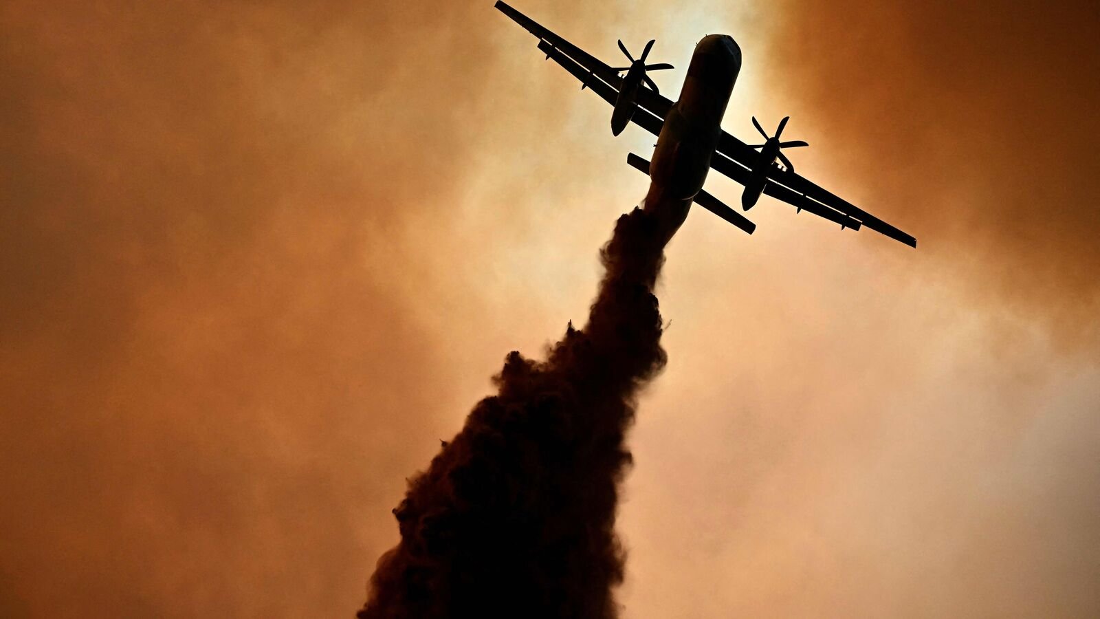 This photograph shows a canadair of the French civil security droping fire retardant over a wildfire near Fontjoncouse, southwestern France, on August 6, 2025. A wildfire has killed one person and injured nine others, scorching 11,000 hectares as firefighters work to contain the blaze, local officials said. The fire, which started the day before, has destroyed or damaged 25 homes in the southern Aude department, where more than 1,800 firefighters have been battling to control what is now the largest wildfire in France this summer.