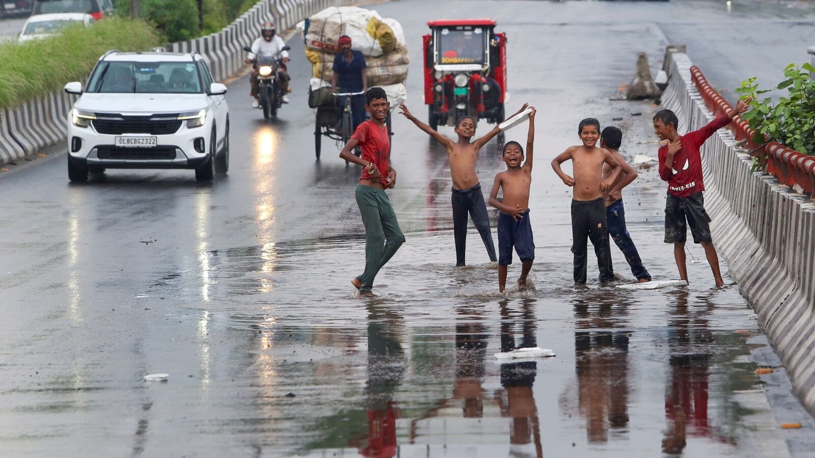 Children play in rainwater collected on a road in New Delhi
