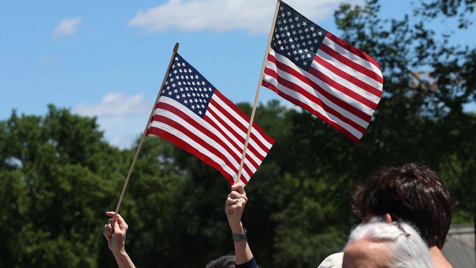 Women wave US national flags during Rolling To Remember, formerly known as Rolling Thunder, a ride to raise awareness of mental health issues among veterans during Memorial Day weekend, in Washington, DC, on May 25, 2025. (Photo by Alex Wroblewski / AFP)