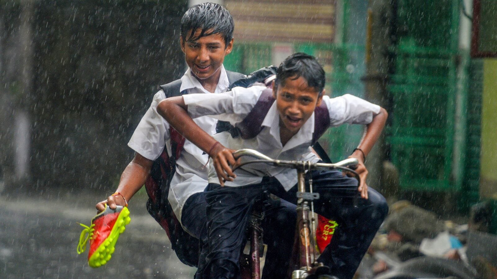 Siliguri: Students make their way amid rainfall, the IMD predicts extremely heavy rainfall in various districts until August 15. (PTI Photo)