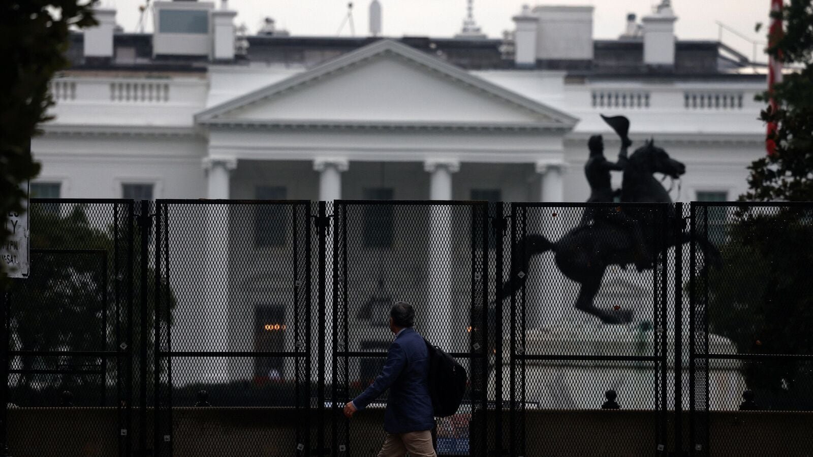 A man walks next to the anti-climb fence placed near the White House, in Washington, D.C. U.S., September 24, 2025. REUTERS/Daniel Becerril