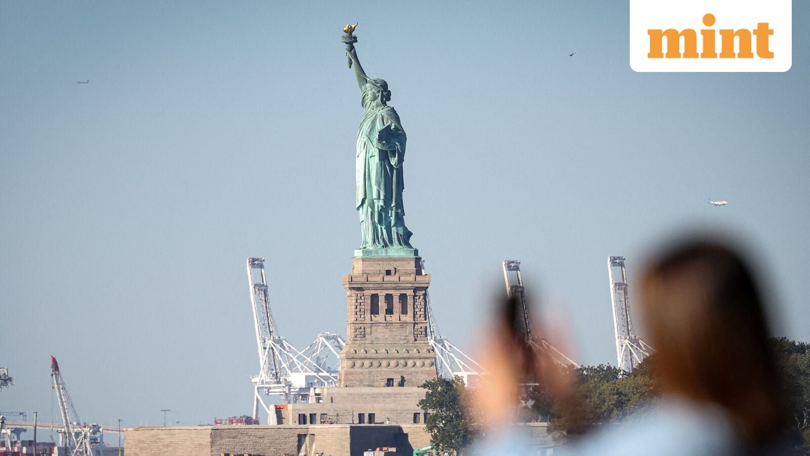 A woman photographs the Statue of Liberty from Battery Park during the first day of a partial U.S. government shutdown in New York City, New York, U.S., October 1, 2025.