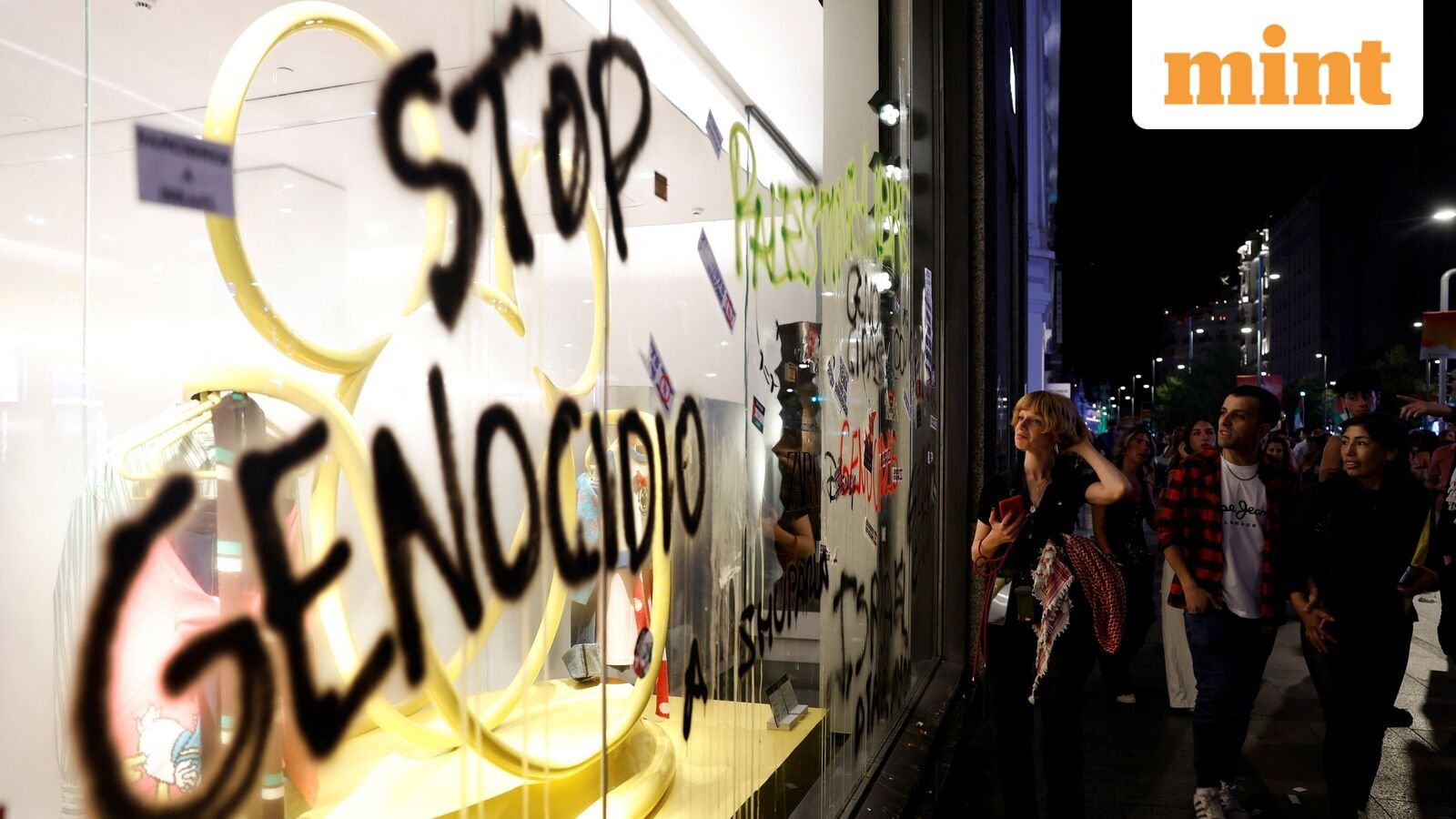 Protesters look at graffiti on the glass window of a store during a demonstration in support of Palestinians and to condemn Israeli forces' interception of the Global Sumud Flotilla vessels, which were aiming to reach Gaza and break Israel's naval blockade, a in Madrid, Spain, October 4, 2025. REUTERS/Susana Vera